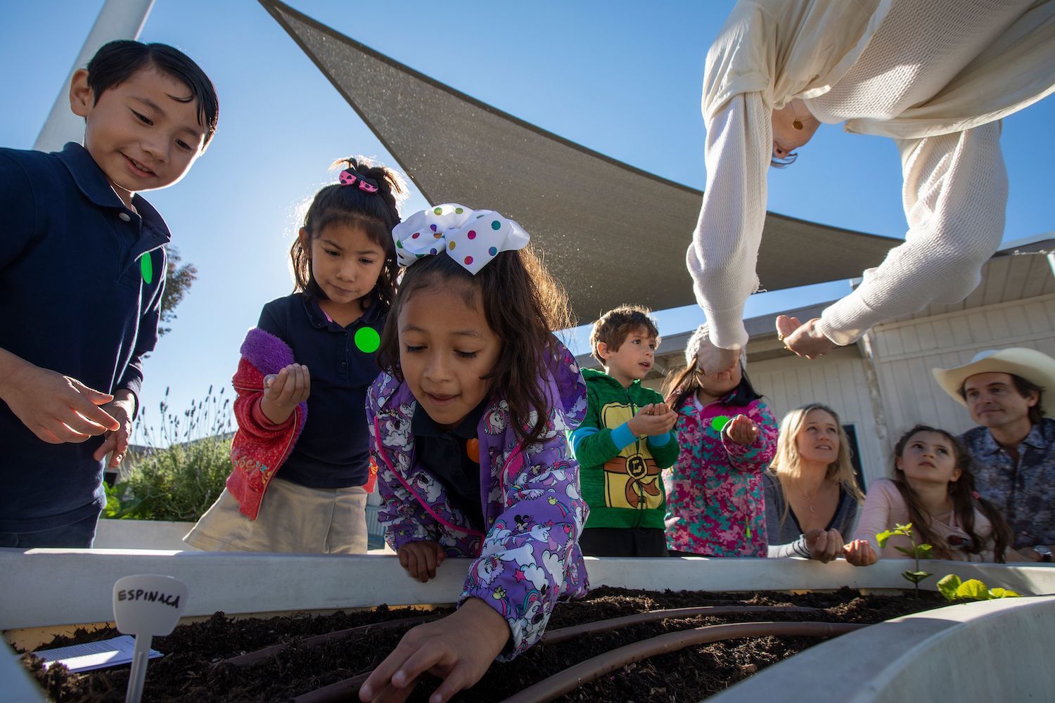 Kimbal Musk (R), wife Christiana and daughter Stella, 6, look on as students at Eucalyptus Elementary School learn to plant a vegetable garden in preparation for Plant a Seed Day in Hawthorne, California on March 13, 2019.