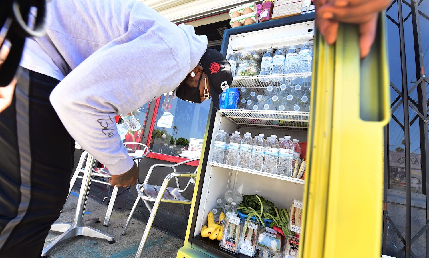 Solo Morris holds the fridge door open as Danny Dierich stocks it with more items on July 16, 2020 outside the Little Amsterdam Coffee shop in Los Angeles, California. October 2021
