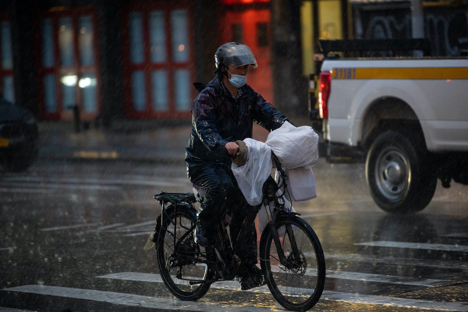 A delivery driver rides a bicycle through the rain on March 24, 2021 in New York City. OCTOBER 2021