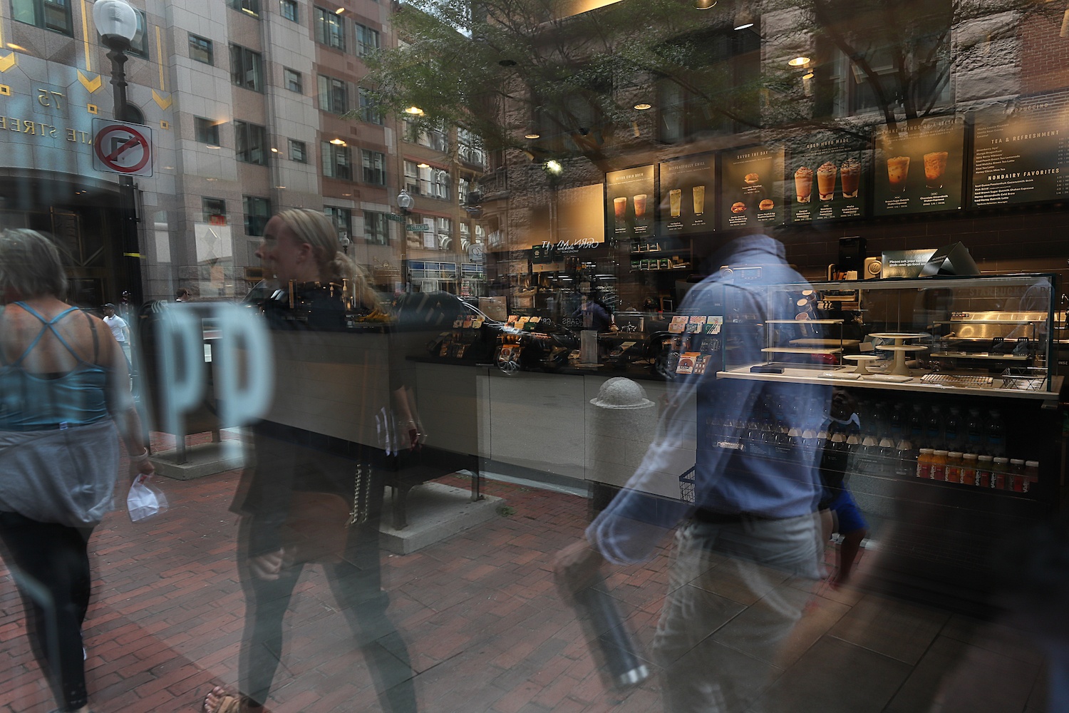 Workers and tourists are reflected in the window of a temporarily closed Starbucks on State Street in Boston on August 9, 2021.