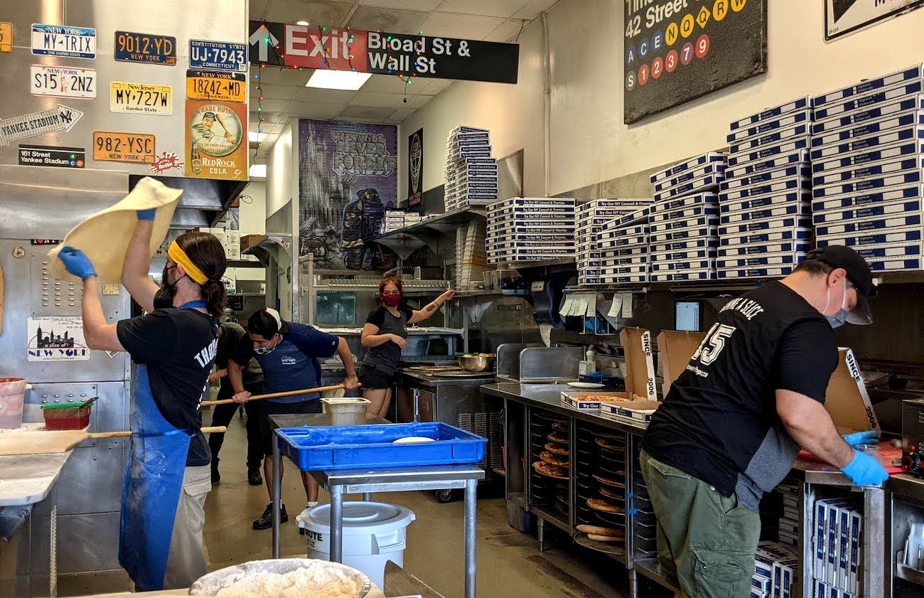 Workers at A Slice of New York making pizza in the kitchen. All wearing masks and gloves. October 2021