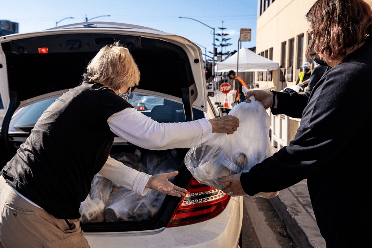 women handing out groceries from trunk of car social 111021