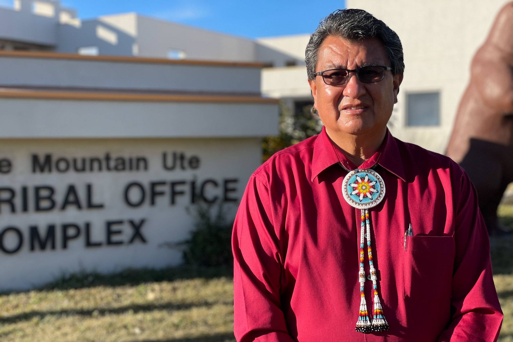 Chairman Manuel Heart of the Ute Mountain Ute Indian Tribe in red collar shirt stands in front of the tribal office complex December 2021.