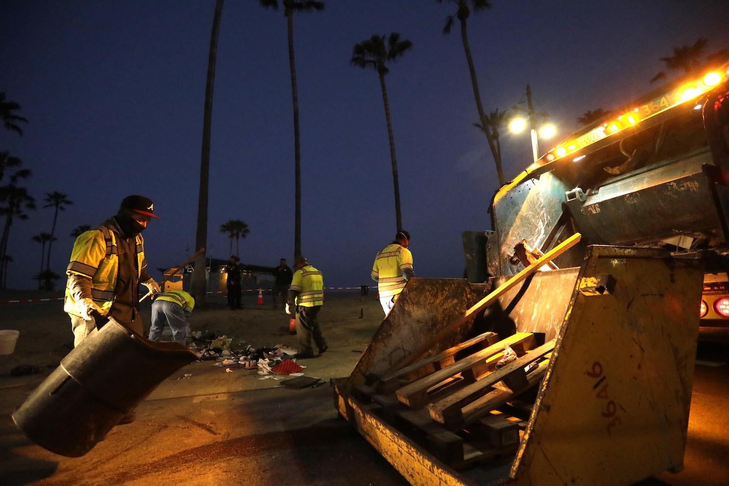 Sanitation workers clear a homeless encampment along Ocean Front Walk around 5 a.m. in Venice on July 8, 2021.