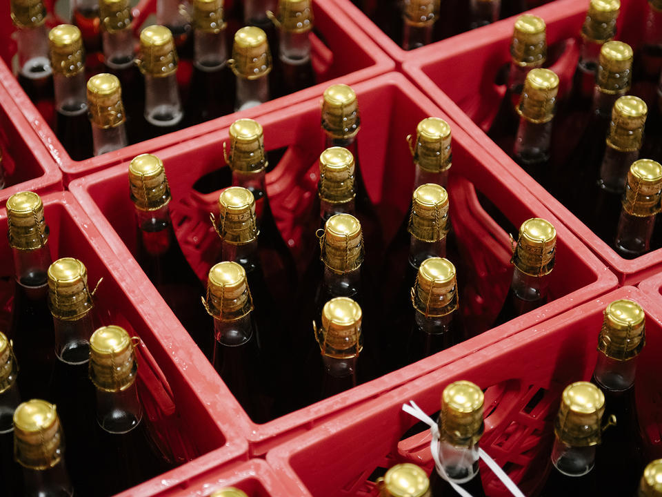 Completed bottles of cider with golden tops in red crates at Finnriver Farm and Cidery in Chimacum, Washington December 2021.