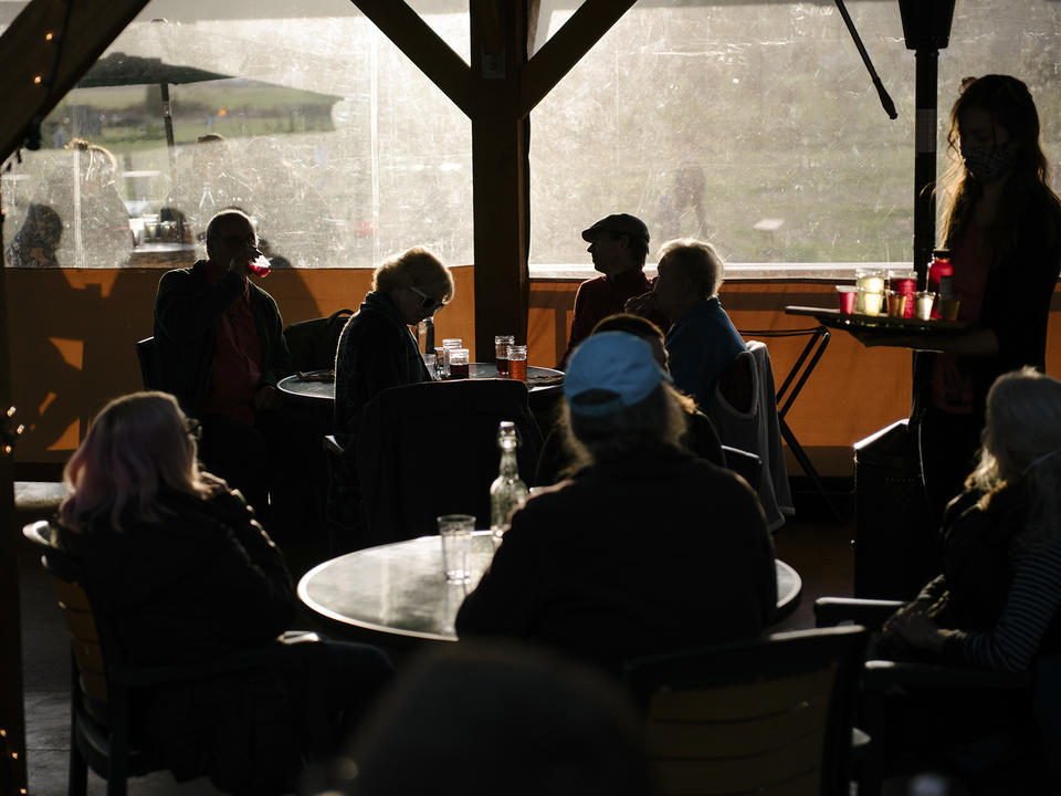 Dark silhouettes of people enjoying live music, food, and cider made next door at Finnriver Farm and Cidery in Chimacum, Washington December 2021.
