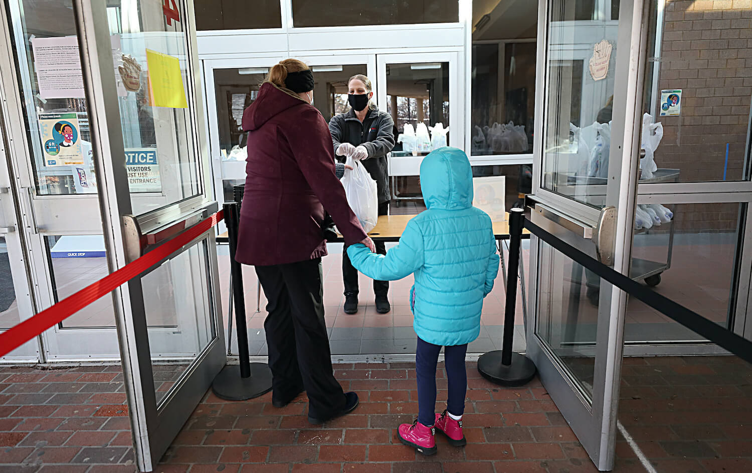BOSTON - DECEMBER 11: A student and her mother collect her breakfast and lunch at her elementary school in Revere, MA on Dec. 11, 2020. December 2021