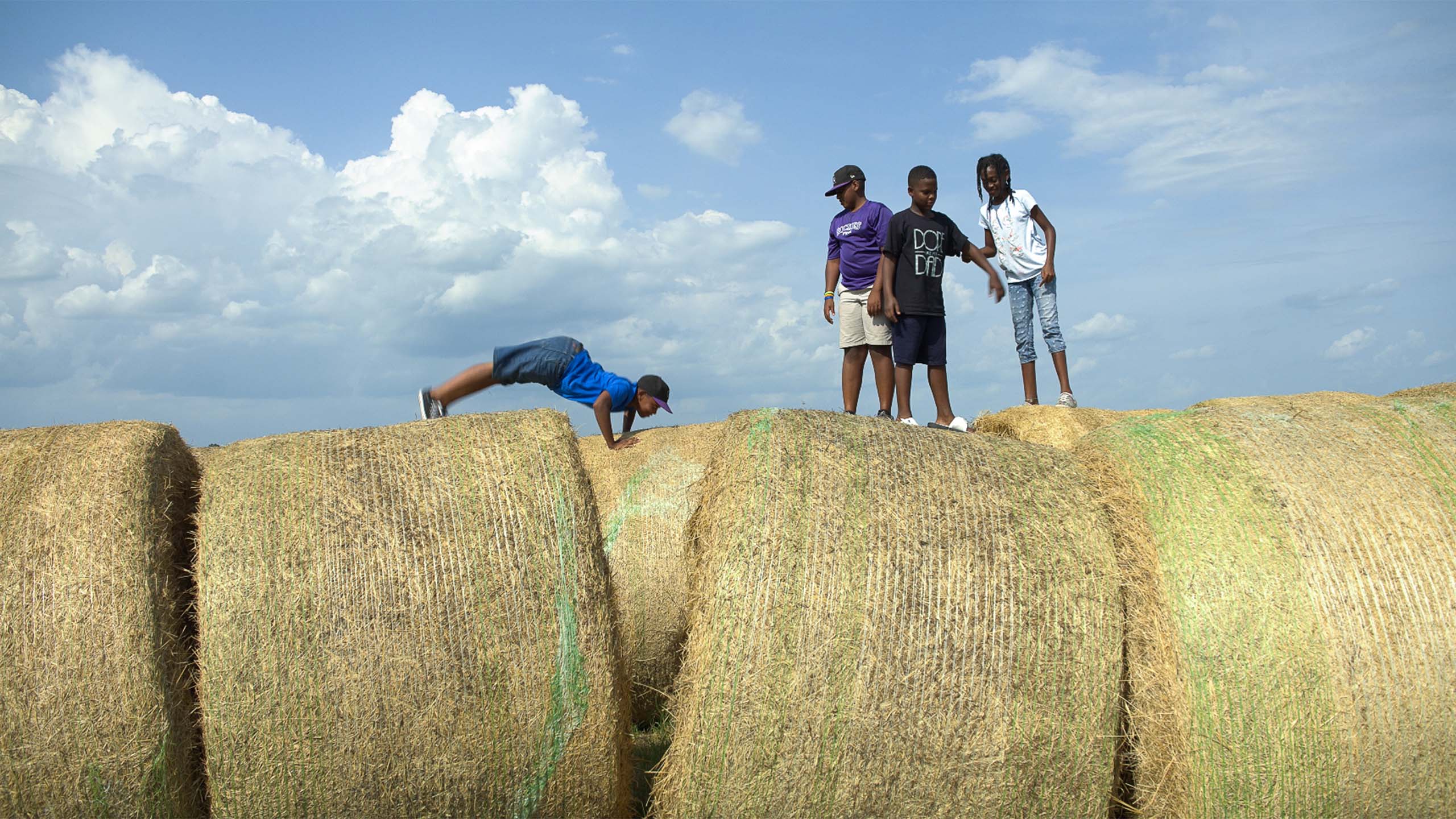 Kimberly Ratcliff and Jeremy Coleman's children play together on barrels of hay. July 2019