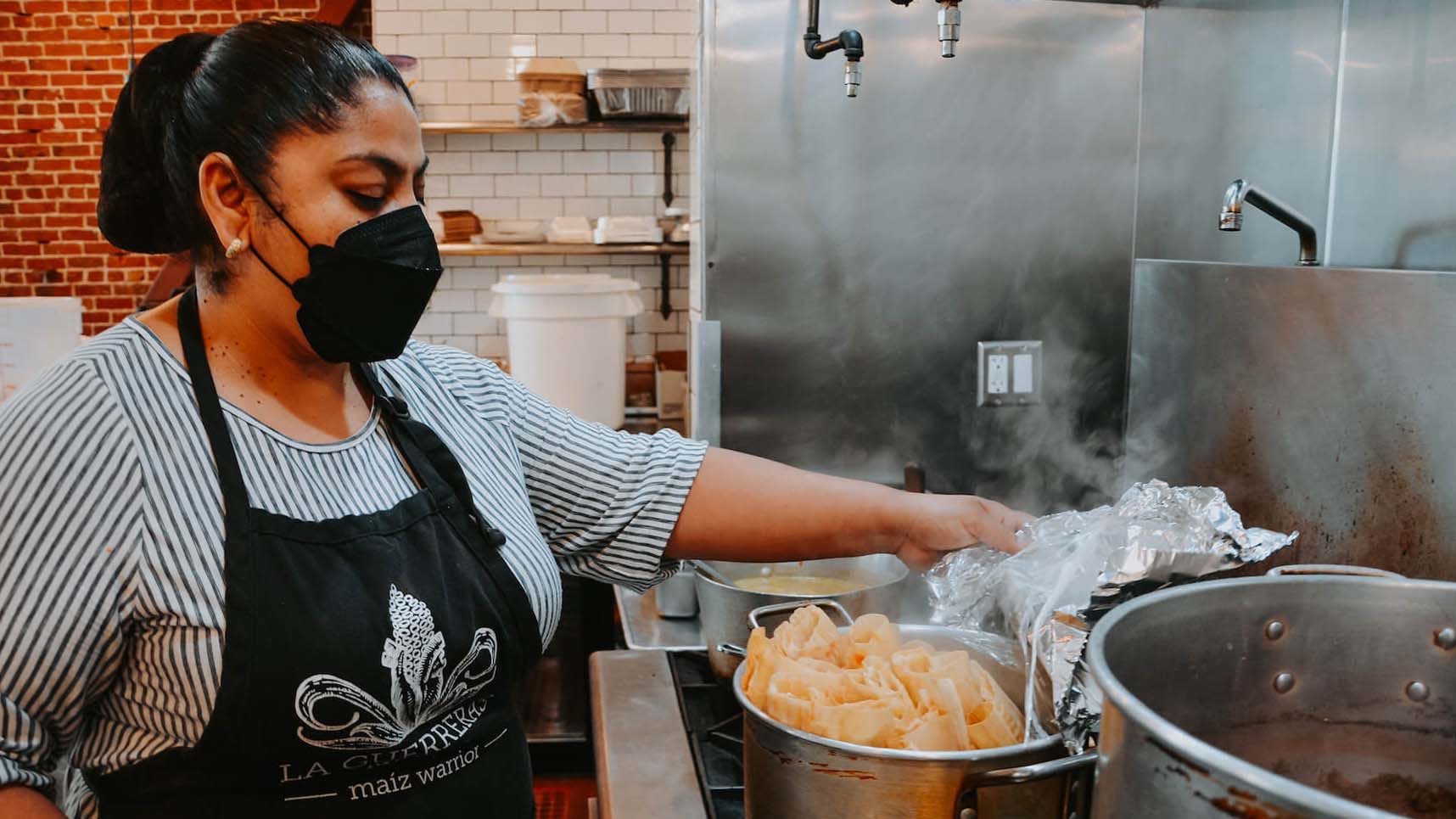 Ofelia Barajas shows tamales on stove at La Guerrera's Kitchen in Oakland, CA. August 2021