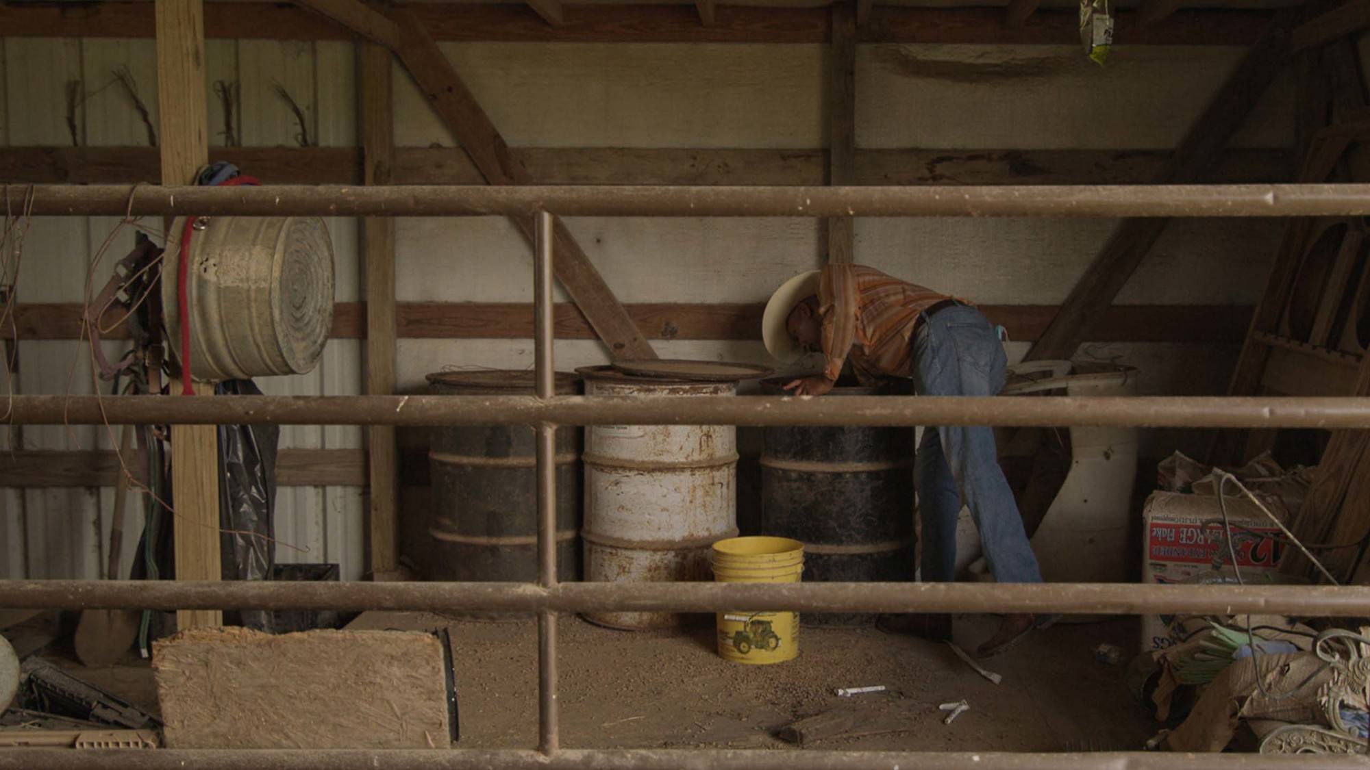 Eddie Jones reaching for feed to for his horses in stable in East Texas. September 2020