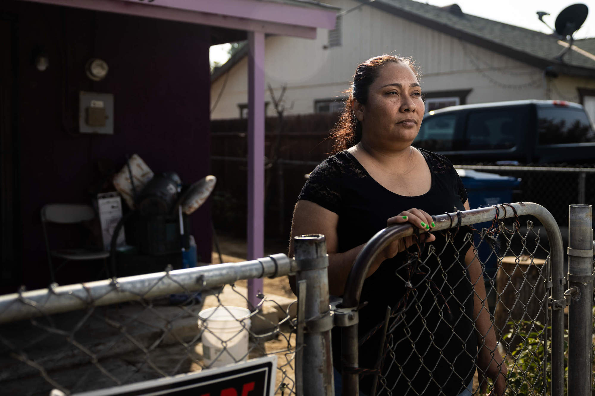 Rosa Perez worries while standing by fence and in black shirt what many years of consuming the tap water in Fuller Acres February 2022 social.