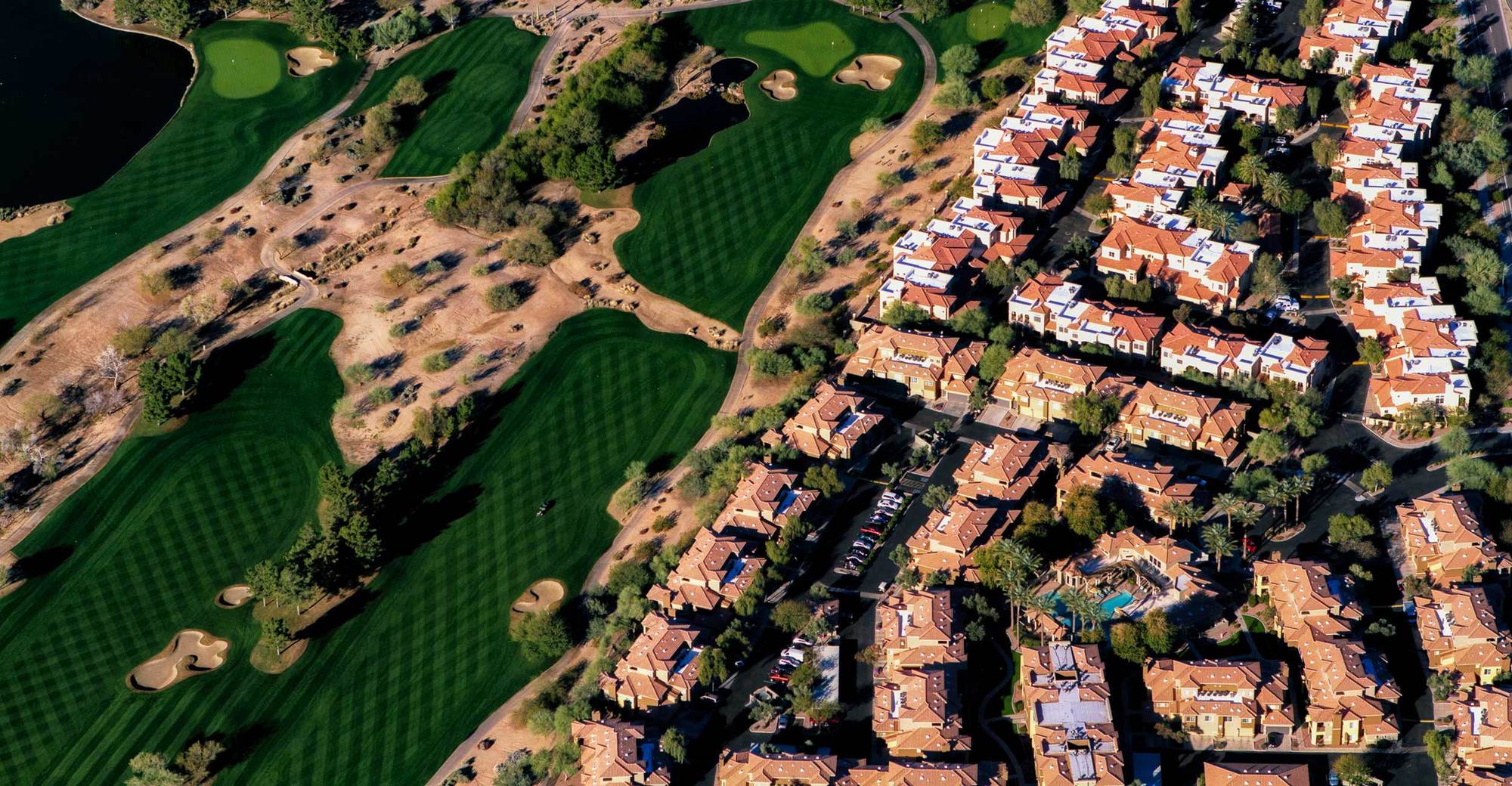 Aerial shot of well kept green golf courses in arizona next to developments March 2022