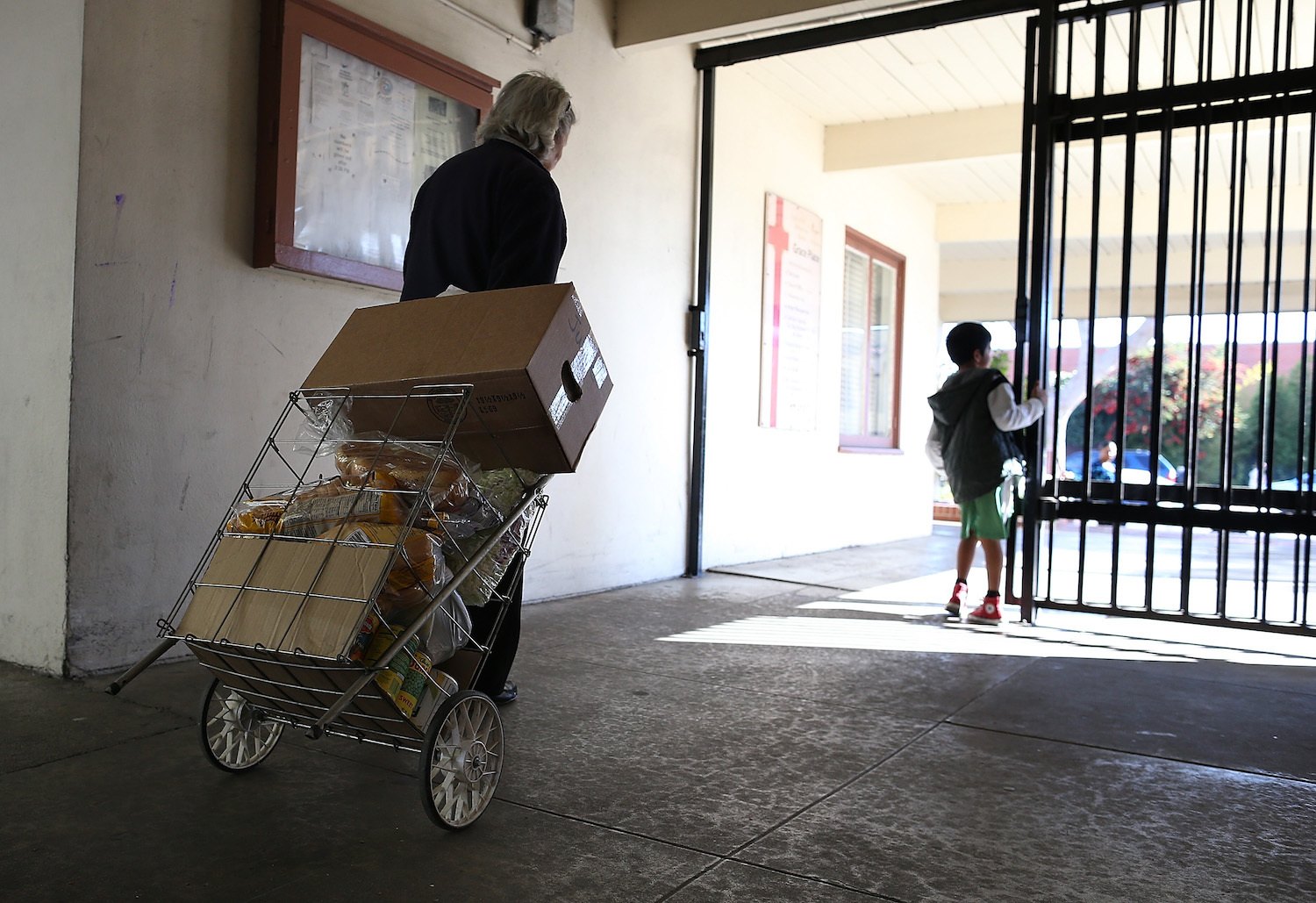 A woman pulls a cart filled with free food that she received at the Richmond Emergency Food Bank on November 1, 2013 in Richmond, California.